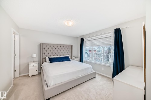 Carpeted bedroom featuring a large window, neutral wall paint, and a built-in overhead light fixture - 3278 Cherry Crescent, Edmonton, AB - Indoor Photo Showing Bedroom