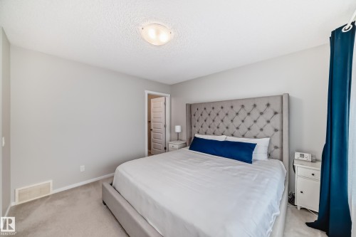 Room featuring neutral wall tones, textured ceiling, light-colored carpeting, a doorway with a paneled door, and a flush-mount ceiling light fixture - 3278 Cherry Crescent, Edmonton, AB - Indoor Photo Showing Bedroom