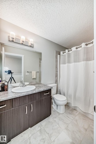 Bathroom featuring a dark wood-finish vanity with a single basin sink, a gray stone-look countertop, and a large wall-mounted mirror - 3278 Cherry Crescent, Edmonton, AB - Indoor Photo Showing Bathroom