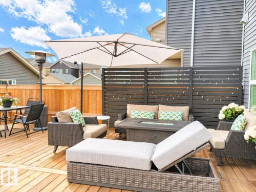 Expansive wood-finish deck with privacy fencing and a dedicated lounging area featuring a built-in fire pit - 3278 Cherry Crescent, Edmonton, AB - Outdoor With Deck Patio Veranda With Exterior