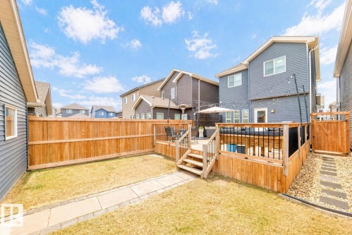 Expansive backyard featuring a multi-level wooden deck with black metal and glass railings, a concrete paver walkway, and a wooden privacy fence - 3278 Cherry Crescent, Edmonton, AB - Outdoor With Deck Patio Veranda With Exterior