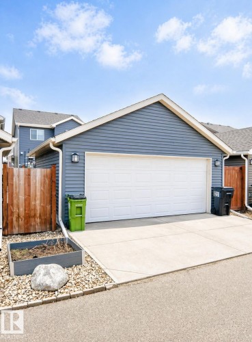 Detached garage featuring blue horizontal siding, white trim, a white garage door, and two exterior wall sconces - 3278 Cherry Crescent, Edmonton, AB - Outdoor