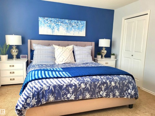 Bedroom featuring a deep blue accent wall and neutral carpeting - 144 Kirpatrick Way, Leduc, AB - Indoor Photo Showing Bedroom