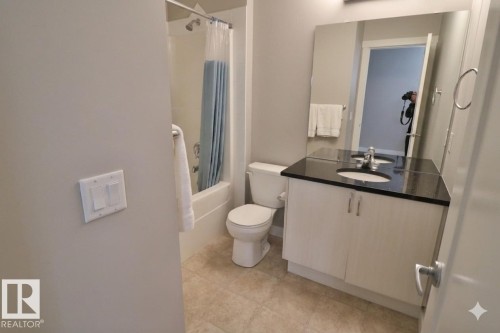 Full bathroom featuring a white vanity with a black countertop, integrated sink, and chrome faucet - 81 446 Allard Blvd, Edmonton, AB - Indoor Photo Showing Bathroom