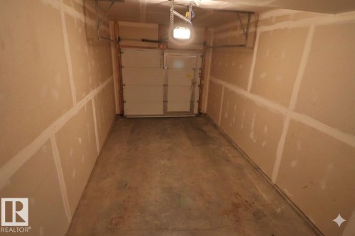 Single-car garage featuring a concrete floor, unpainted drywall walls, and an overhead garage door - 81 446 Allard Blvd, Edmonton, AB - Indoor Photo Showing Garage