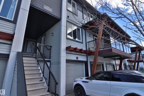 Contemporary multi-level residence featuring light gray siding, an integrated garage, and a private entrance with exterior stairs - 81 446 Allard Blvd, Edmonton, AB - Outdoor