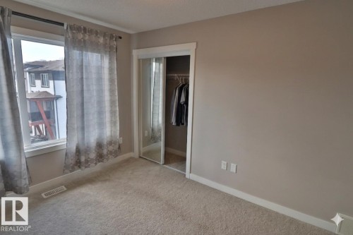 Carpeted room with a double window, neutral wall tones, and a mirrored closet - 81 446 Allard Blvd, Edmonton, AB - Indoor Photo Showing Other Room