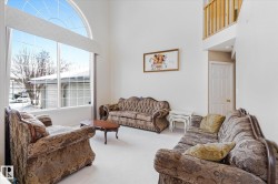 The living room features high ceilings and a large arched window - 