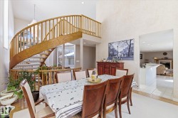 The dining area features a prominent wooden spiral staircase with railings - 