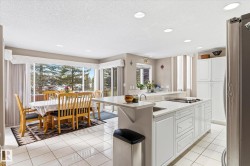 Spacious kitchen and dining area with white tiled flooring, recessed lighting, and large windows providing abundant natural light and exterior views - 