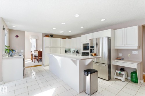 The property features a bright kitchen with white cabinetry, a large kitchen island, and stainless steel appliances - 128 Weaver Drive, Edmonton, AB - Indoor Photo Showing Kitchen With Upgraded Kitchen