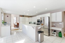 The property features a bright kitchen with white cabinetry, a large kitchen island, and stainless steel appliances - 