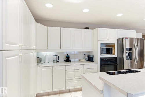 Kitchen featuring white cabinetry, light-colored countertops, recessed lighting, and a stainless steel refrigerator - 128 Weaver Drive, Edmonton, AB - Indoor Photo Showing Kitchen