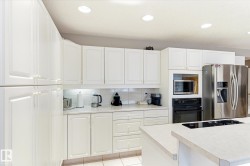 Kitchen featuring white cabinetry, light-colored countertops, recessed lighting, and a stainless steel refrigerator - 