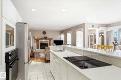 The kitchen features white cabinetry, white tiled flooring, and a built-in cooktop with a sink - 