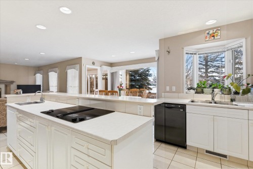 The kitchen features white cabinetry, an electric cooktop on the island, and a dishwasher - 128 Weaver Drive, Edmonton, AB - Indoor Photo Showing Kitchen With Double Sink