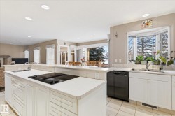 The kitchen features white cabinetry, an electric cooktop on the island, and a dishwasher - 