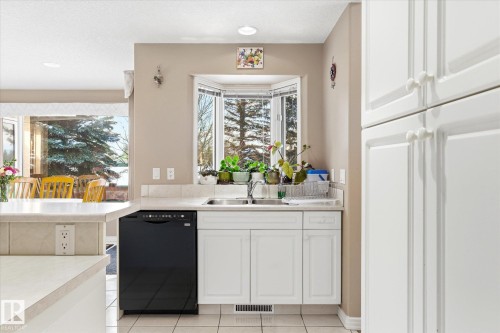 The kitchen features white cabinetry, a black dishwasher, and a bay window above the sink - 128 Weaver Drive, Edmonton, AB - Indoor