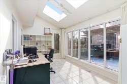This bright room features a vaulted ceiling with two skylights, track lighting, and tiled flooring - 