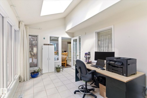 Bright sunroom featuring white tiled flooring, a vaulted ceiling with a skylight, and expansive windows - 128 Weaver Drive, Edmonton, AB - Indoor Photo Showing Office