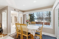 The dining area features large windows offering extensive views of the snowy outdoors, tiled flooring, and recessed lighting - 