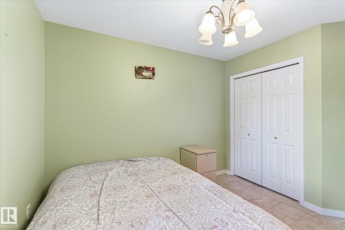 This room features light green walls, tiled flooring, and a ceiling-mounted light fixture - 128 Weaver Drive, Edmonton, AB - Indoor Photo Showing Bedroom