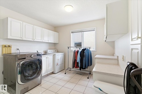 Utility room featuring tiled flooring, a window, and white cabinetry - 128 Weaver Drive, Edmonton, AB - Indoor Photo Showing Laundry Room
