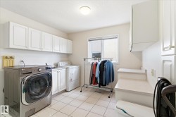Utility room featuring tiled flooring, a window, and white cabinetry - 