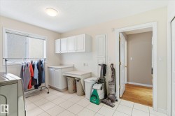The laundry area features white cabinetry, a window, and tiled flooring - 