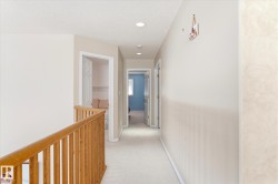 Hallway featuring light-colored carpeting, recessed lighting, and a wooden handrail - 