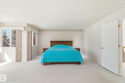 Expansive bedroom featuring carpeted flooring, large windows, and an open doorway - 