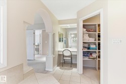 This area features an arched entryway, tiled flooring, and a built-in vanity with a mirror - 