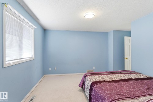 Bright room featuring a window with white blinds, light blue walls, and light-colored carpeting - 128 Weaver Drive, Edmonton, AB - Indoor Photo Showing Bedroom