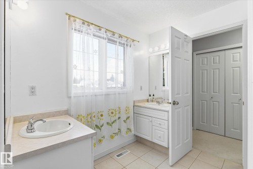 Bathroom featuring a window providing natural light, two distinct vanity areas, and tiled flooring - 128 Weaver Drive, Edmonton, AB - Indoor Photo Showing Bathroom
