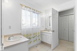 Bathroom featuring a window providing natural light, two distinct vanity areas, and tiled flooring - 