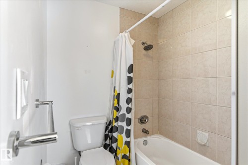 Bathroom featuring a toilet, a bathtub with a shower, and tiled walls - 128 Weaver Drive, Edmonton, AB - Indoor Photo Showing Bathroom