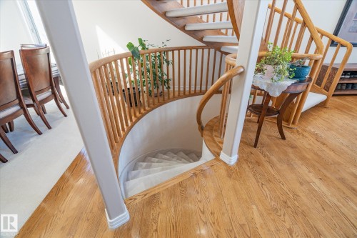 The property features hardwood flooring and a curved staircase with a light wood banister and carpeted treads - 128 Weaver Drive, Edmonton, AB - Indoor Photo Showing Other Room