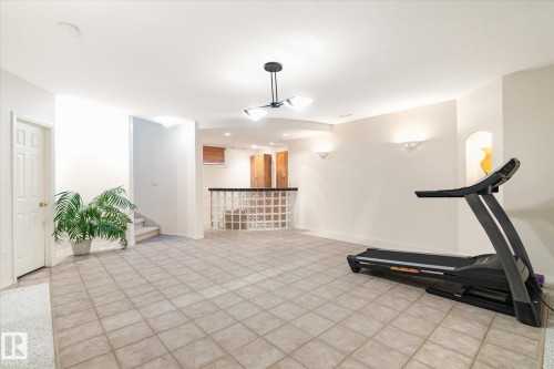 Spacious room with tiled flooring and a built-in bar featuring glass block construction - 128 Weaver Drive, Edmonton, AB - Indoor Photo Showing Gym Room