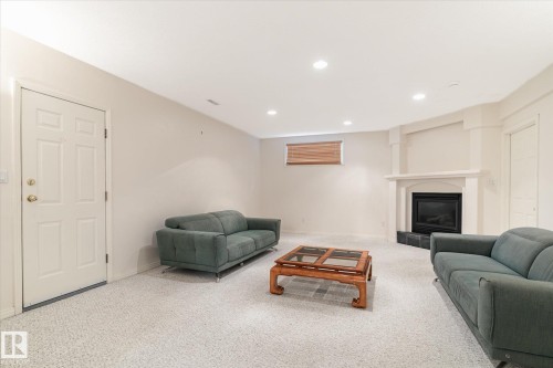 The property features a spacious living area with light-colored carpeting, recessed lighting, and a fireplace with a mantel - 128 Weaver Drive, Edmonton, AB - Indoor With Fireplace