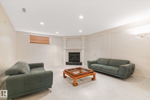 Spacious living area featuring light-colored walls, recessed lighting, and a corner fireplace with a white mantel and black hearth - 128 Weaver Drive, Edmonton, AB - Indoor With Fireplace