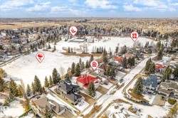 Aerial view showcasing the property situated within a developed neighborhood featuring snow-covered landscapes, mature trees, and a visible street - 