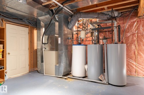 The property includes a utility area with three water heaters and exposed ductwork - 128 Weaver Drive, Edmonton, AB - Indoor Photo Showing Basement
