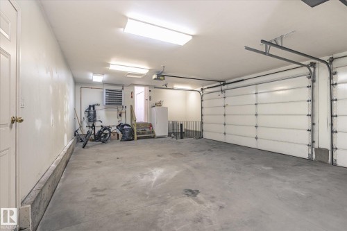 The property includes a spacious garage with a concrete floor, two overhead garage doors, and overhead lighting fixtures - 128 Weaver Drive, Edmonton, AB - Indoor Photo Showing Garage