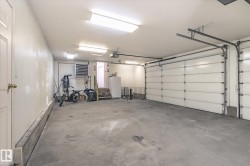 The property includes a spacious garage with a concrete floor, two overhead garage doors, and overhead lighting fixtures - 