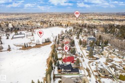 Aerial view showcasing the property situated within a developed residential area, featuring a street lined with homes and mature trees - 