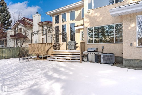 The property features a spacious rear deck with wooden railings, leading down to a snow-covered yard - 128 Weaver Drive, Edmonton, AB - Outdoor