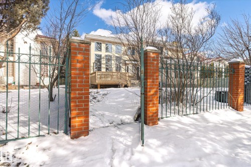 The property features a gated entrance with brick pillars and a metal fence - 128 Weaver Drive, Edmonton, AB - Outdoor