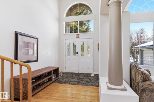 The property features a grand entryway with double doors and an arched transom window, complemented by a large decorative column - 128 Weaver Drive, Edmonton, AB - Indoor Photo Showing Other Room