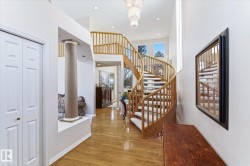 Welcoming entryway featuring a prominent spiral staircase with wood banisters, hardwood flooring, and a decorative chandelier - 