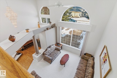 Living area featuring high ceilings, large windows with arch-top elements, and a decorative chandelier - 128 Weaver Drive, Edmonton, AB - Indoor Photo Showing Other Room